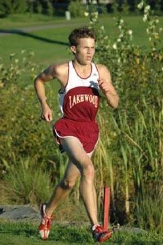 Senior harrier Davis Dye strides it out along a water hazard at the Cedarcrest Golf Course Thursday