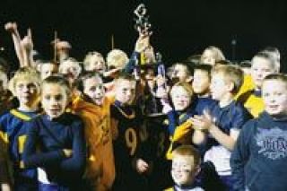 Members of the victorious Arlington Blue 9-10 year-old midget league team hoist their trophy in celebration Saturday