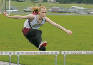 Hurdler Amanda Gregory hurdles in soggy conditions during the Lakewood track meet with Sultan.
