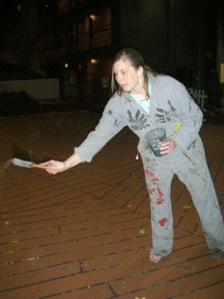 Arlington High School senior Eden Moss spatters paint on the set floor to bring out the color of the sets for the schools production of Our Town