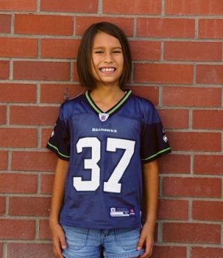 Aspen Carbahal poses for a photo wearing her favorite players Shawn Alexanders jersey.