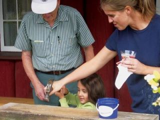 Pioneer Harley Robb helps Amari Garrissey hammer nails while foster grandmother Lynne Glaze looks on at Pioneer Days