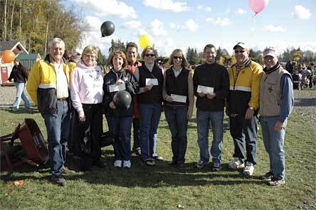 Representatives of the Arlington School District are flanked by members of the Marysville Noon Rotary as they brandish their checks from 'Pumpkins for Literacy' at the Smokey Point Plant Farm Oct. 25
