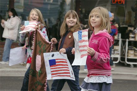 Three girls show off their American flag drawings during the Arlington Veterans Day parade Wednesday