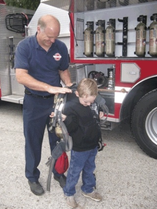 Photo courtesy the Cowen family.  Arlington firefighter Cary Stuart helps Trafton Elementary first-grader Wes Cowen try on an oxygen tank Sept. 19.