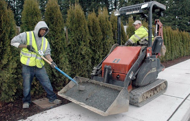 Telecom Technician Ron Konch shovels gravel provided by Brian Warnock on the west side of 67th Avenue on Feb. 19.