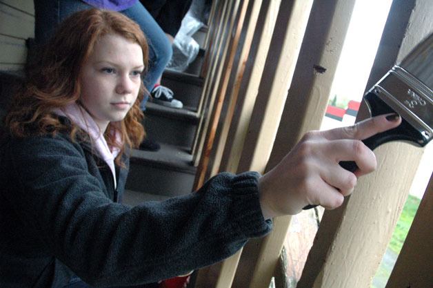 Arlington High School junior Anna Deeter touches up the staircase railing of a century-plus-old building in downtown Arlington on April 19.