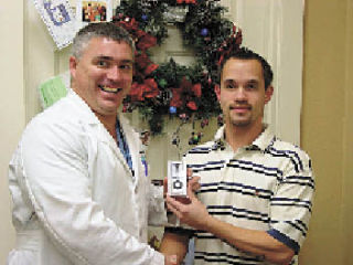Dr. Jeff Cartwright presents a Silver iPod Nano to James Schwahn after selling tickets for a raffle to raise money for the Arlington Food Bank at his Advanced Orthopedic Institute office in Arlington. The Arlington Chiropractic office of Dr. Shawn Gay also participated in the project. The clinics collected 222 pounds of food and $320 cash