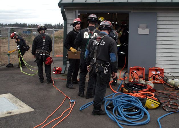 Firefighters don their gear for a simulated confined space rescue at a dry well provided by the city of Arlington Public Works Department.