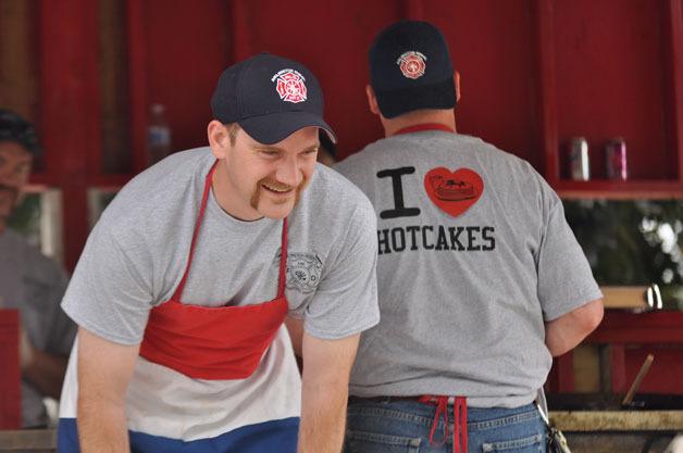 Fire District 21 Commissioner Eric Nordstrom dons an apron and serves up pancakes at the Arlington Heights Firefighters Association Pancake Breakfast at Haller Park on July 4.
