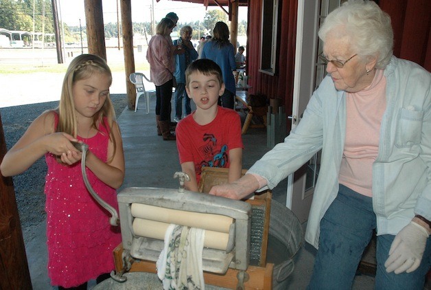 Londyn and Marcus Camp's efforts on an old-fashioned washboard and clothes-wringer are supervised by Joann Gray during the Stillaguamish Valley Pioneer Museum's 'Pioneer Days' Sept. 20.