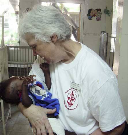 Arlington resident Jean Wessel holds a 9-month-old baby in Dessalines