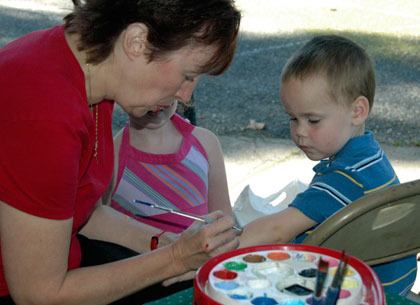 Arlington resident Judy Tilley paints a flaming football on 3-year-old Alex Davis’ arm during the 56th annual Trafton Fair on Saturday