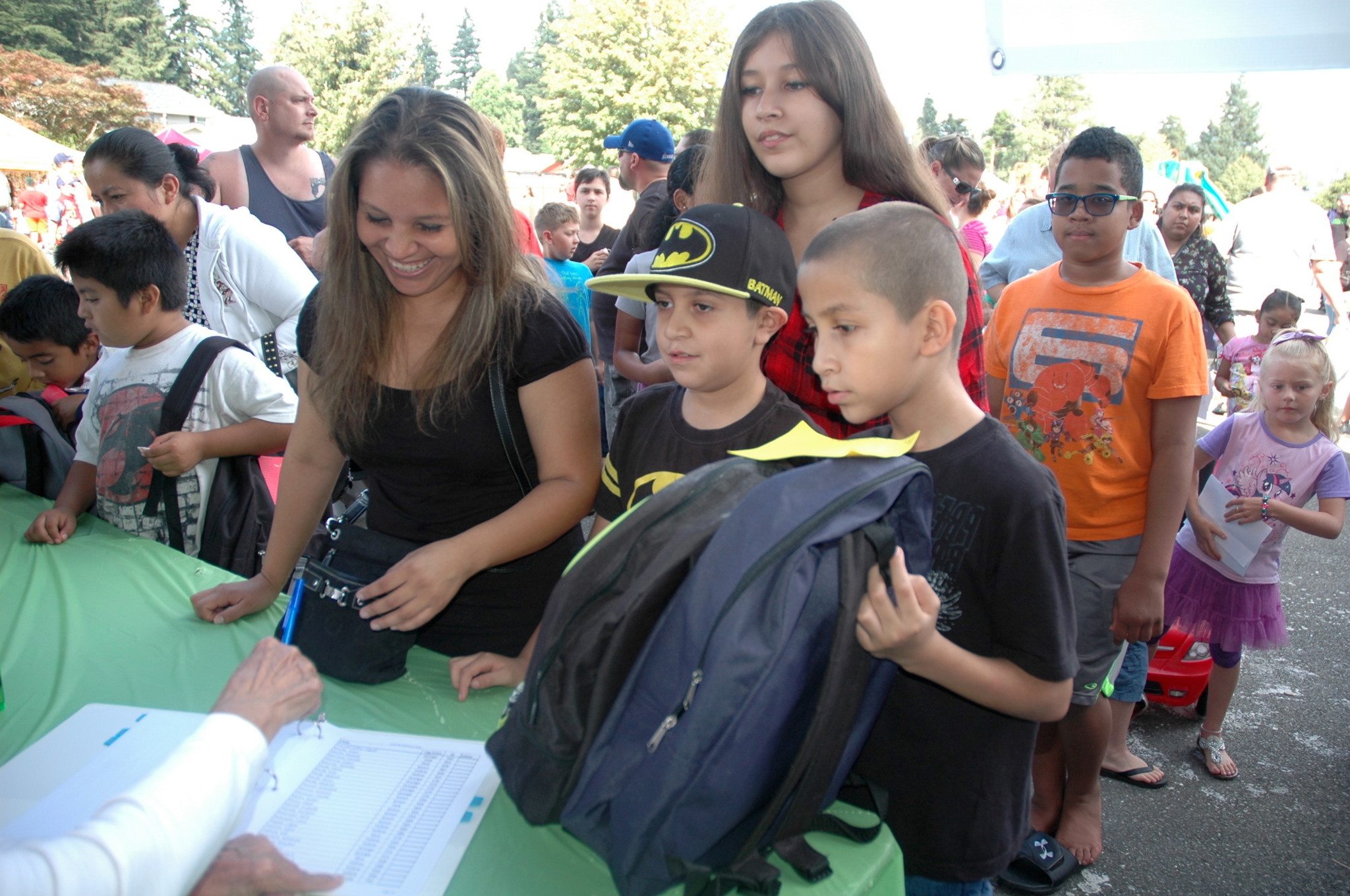 Kirk Boxleitner/Staff PhotoMom Mireya Novoa signs for daughter Daisy and sons Angel and Noah to receive backpacks and school supplies at Presidents Elementary during the annual Arlington Back2School rally Aug. 21.