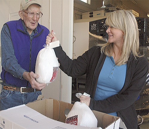 Bill Robison gets handed a turkey by Tonya Shaffer at the Arllngton Food Bank.