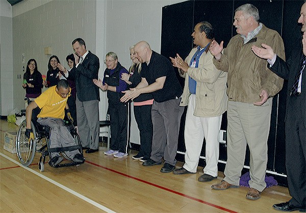 Quinton Morris is cheered on by Marysville YMCA members as he carries 25 pounds of weights behind him for his 'Draggin' Dumbbells for Disabilities' fundraiser March 11.