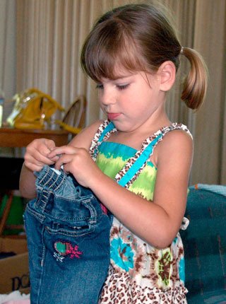 Three-year-old Mia Martin holds a pair of pants that she received from a community member. Mia’s mother