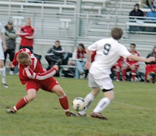 M-P senior defender Jeff Jensen struggles to stay on his feet and maintain possession of the ball as Arlington midfielder James Chesnutt tries to dribble it away.