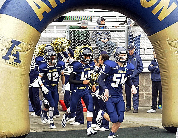 Arlington football players run onto the field through at arch at the start of their game against Glacier Peak.