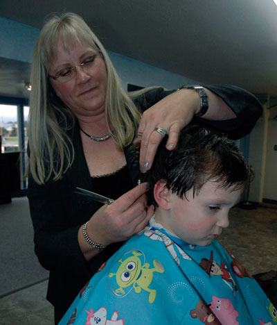 A.J. Matulovich sits patiently for his haircut by Lori Kirkeby at the Hairport Barbershop in Arlington.