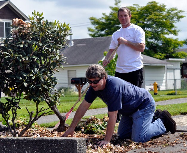 Windermere employees Paul Migrala and Clint Bryson work to clean up Centennial Park.