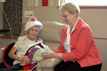 Arlington resident and knitter Alyce Matson shows Cascade Valley Hospital patient Mave Zosel hats that she and her friends have knitted. Matson has donated more than 100 hats to the hospital over the past few years.