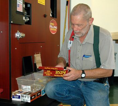 Arlington Tobacco Express customer Kent Pruitt likes to kneel down to collect his cigarettes from the shop’s filling station machine.