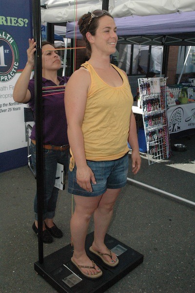 Kathy Starkenburg of Health First Chiropractic in Marysville checks the alignment of Ali Hendricks at the Arlington Street Fair July 11.