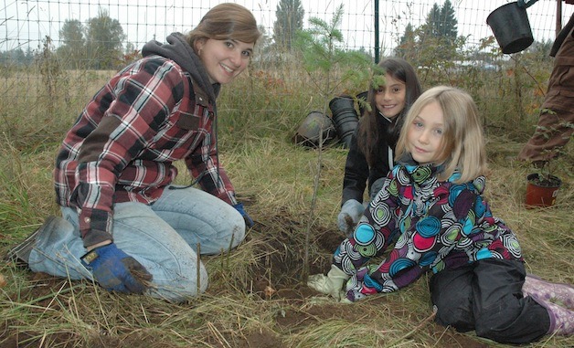 Grace Academy National Honor Society student Piper Wright helped Marshall Elementary third-graders Reya Moore and Savannah Buse plant trees near the banks of Allen Creek last year.