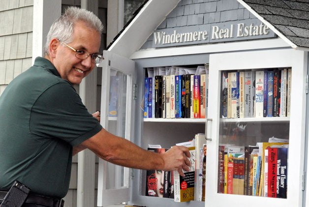 Al Lehman organizes books in the Windermere Real Estate Little Free Library in Arlington.