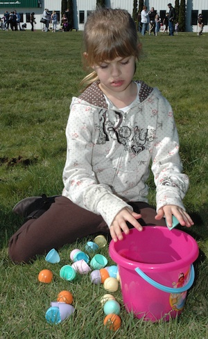 Lucy Wilson opens her Easter eggs after hunting them down at the Arlington Municipal Airport field last year.