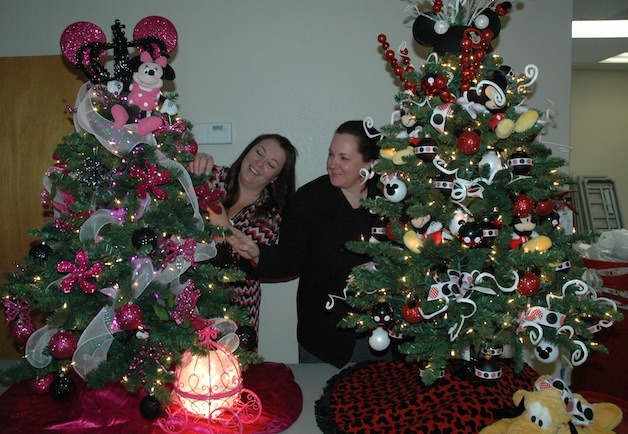 Jennifer Egger and Erika Coghill finish trimming the Mickey and Minnie Mouse Christmas trees in preparation for this year's Festival of Trees.