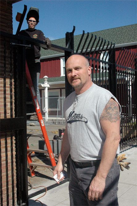 Steve Saunders guides a hired hand installing a fence around his future beer garden.