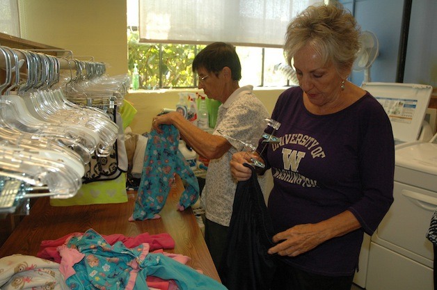 Arlington Kids' Kloset volunteers Lori Emerson and Sally Worthley sort freshly laundered clothes in preparation for the back-to-school shopping season for students on free and reduced-price lunches in the Arlington