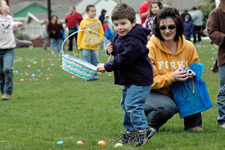 Three-year-old Kody Cummings collects eggs while mom
