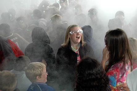 Arlington High School junior Chelcie Nielsen reacts to a chemistry experiment in the covered play area at Presidents Elementary School May 26. The mist came from another student dumping boiling water into a bucket of dry ice.
