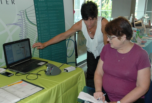 Symmetry Chiropractic’s Juanita Kolbeck shows Mary Mitchell of Arlington the stress on her spine.