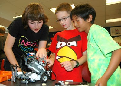 Arlington High School NeoBots Team student mentor Caroline Vogl explained to Sedro-Woolley student Josiah Velogoes and Arlington student Junha Lee the mechanics of their robot at last year’s summer camp.