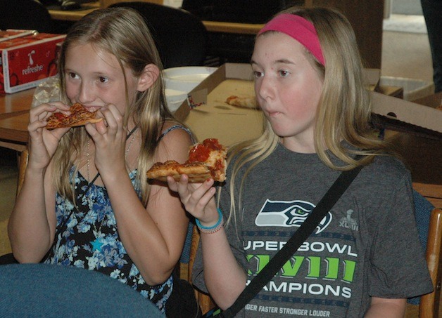 Fiona Marsh and Sierra Schmitz tuck into some pizzas and watch Divergent during the Arlington Library's Aug. 8 closing celebration of its summer reading program.