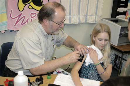 Steve Cooper of Digital Memories gives Post Middle School seventh-grader Sadee Wakefield a temporary tattoo during the Kent Prairie carnival fundraiser.