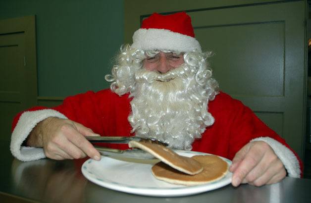 Santa Claus fills in for Recency Care Center Administrator Mike Shaw in serving up pancakes at the Stillaguamish Senior Center on Dec. 8.