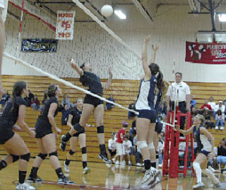 Tomahawk senior hitter Emily Boerger attempts to spike over the outstretched hands by Arlington’s Bree Covey.