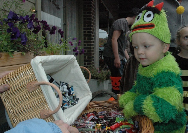 Little green monster Carson Casillas checks out the selection of candy while trick-or-treating on Olympic Avenue during Arlington’s ‘Hometown Halloween.’