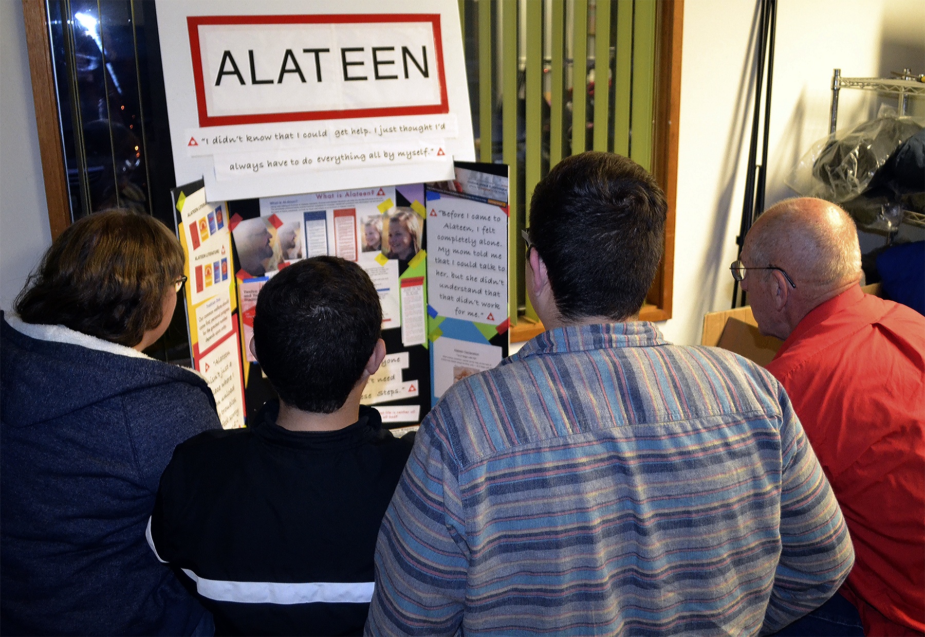 Alateen members and their sponsor look at a poster that was made to let the public know about their meetings. (Steve Powell/Staff Photo)