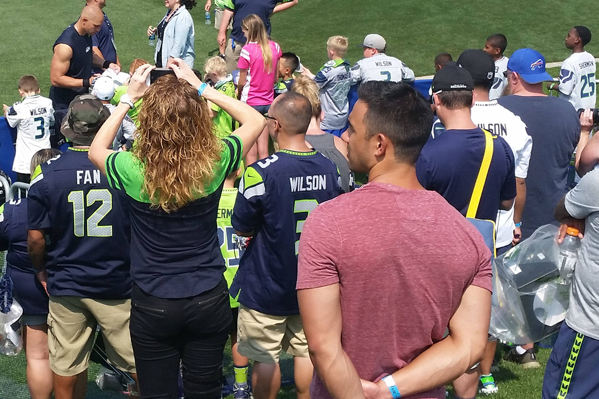 Dozens of fans gather around Jimmy Graham, upper left, as he signs autographs after the training camp practice.