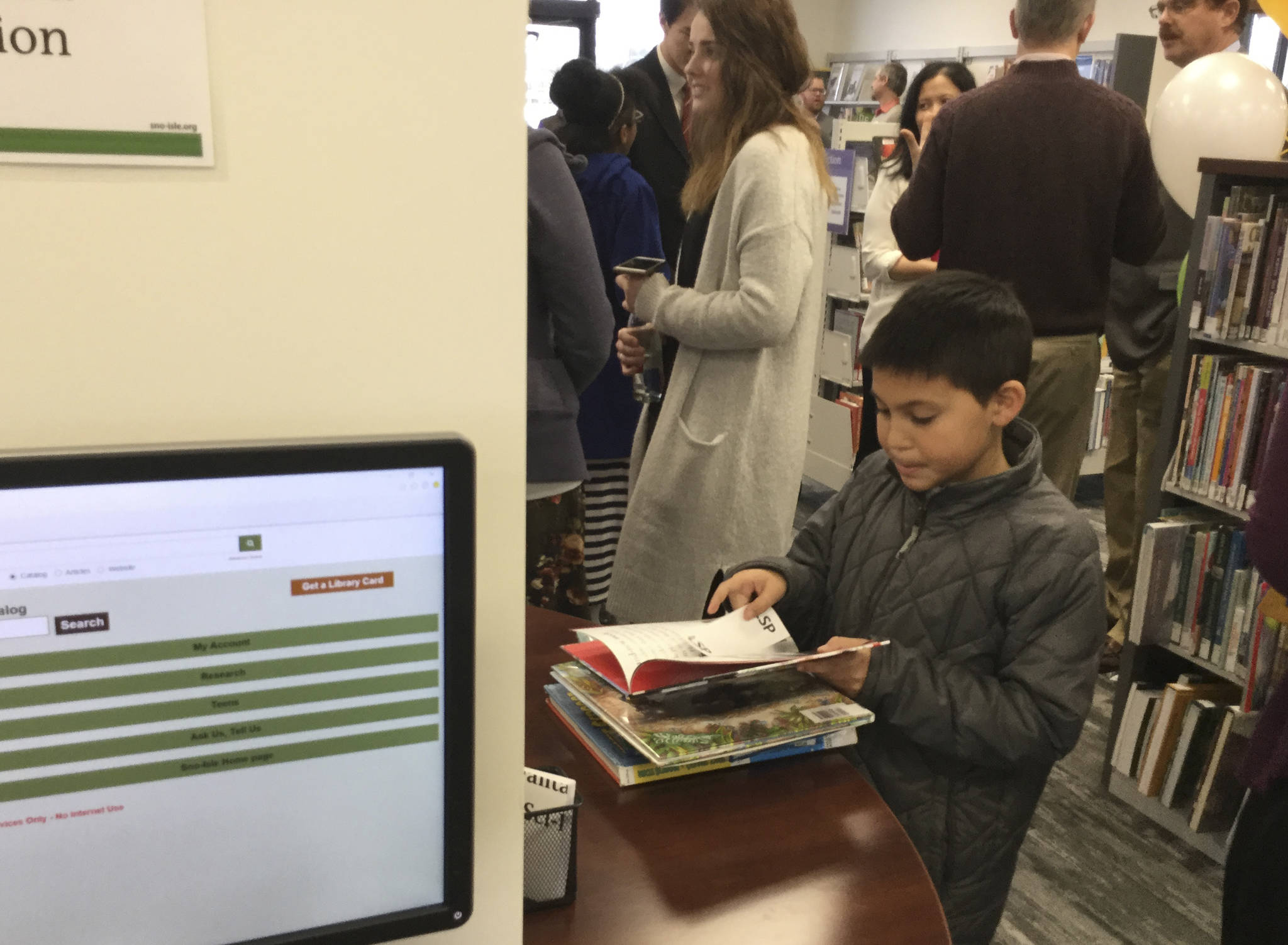 A young reader takes a look at his stack of books before heading to the checkout counter at the Lakewood-Smokey Point Library that celebrated its grand opening on Saturday.