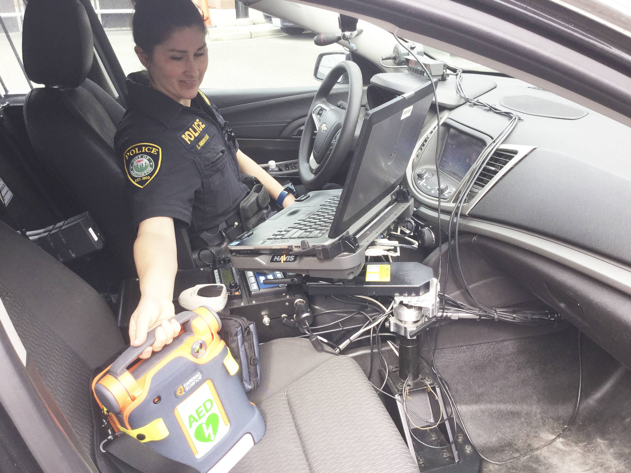 Arlington Police Officer Stephanie Ambrose displays one of the eight new automated external defibrillators (AEDs) that were donated to the department by the Arlington Rotary Club.