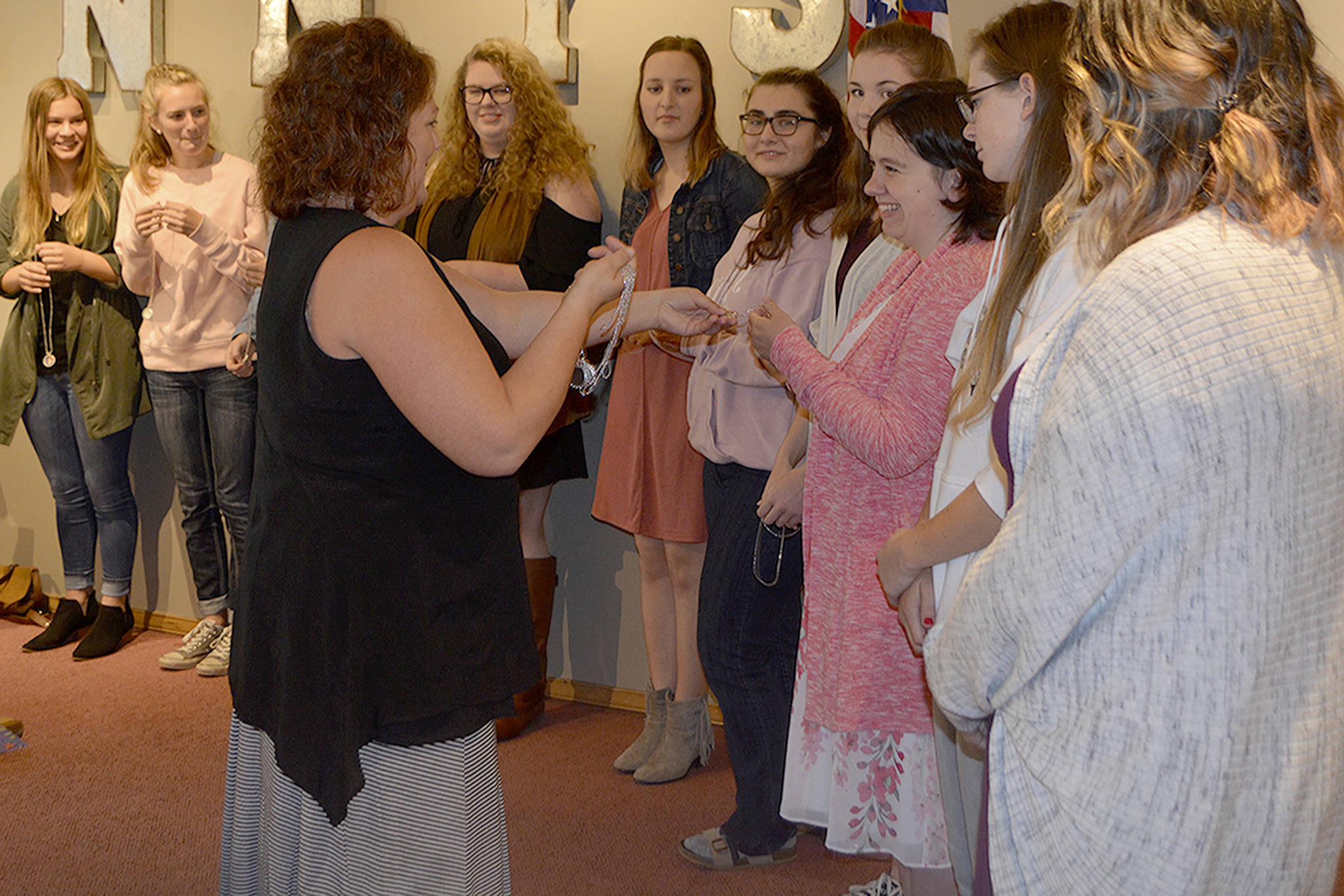 Nancy Schaut hands out Wonder Woman necklaces to Marysville high school graduates who received Soroptimist scholarships Tuesday. Schaut won one in 1988 and returned to the club to help the community. (Steve Powell/Staff Photo)