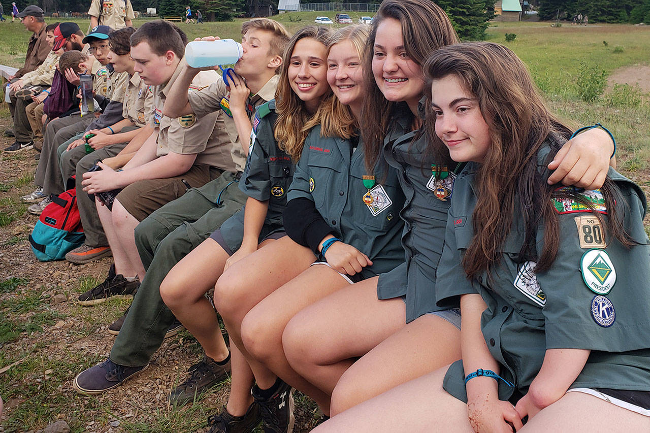 Courtesy Photo                                 Molly McKinney, Natalie Hawkins, Madisen Dawson and Jackie Shea sit on a bench at camp with other Scouts.