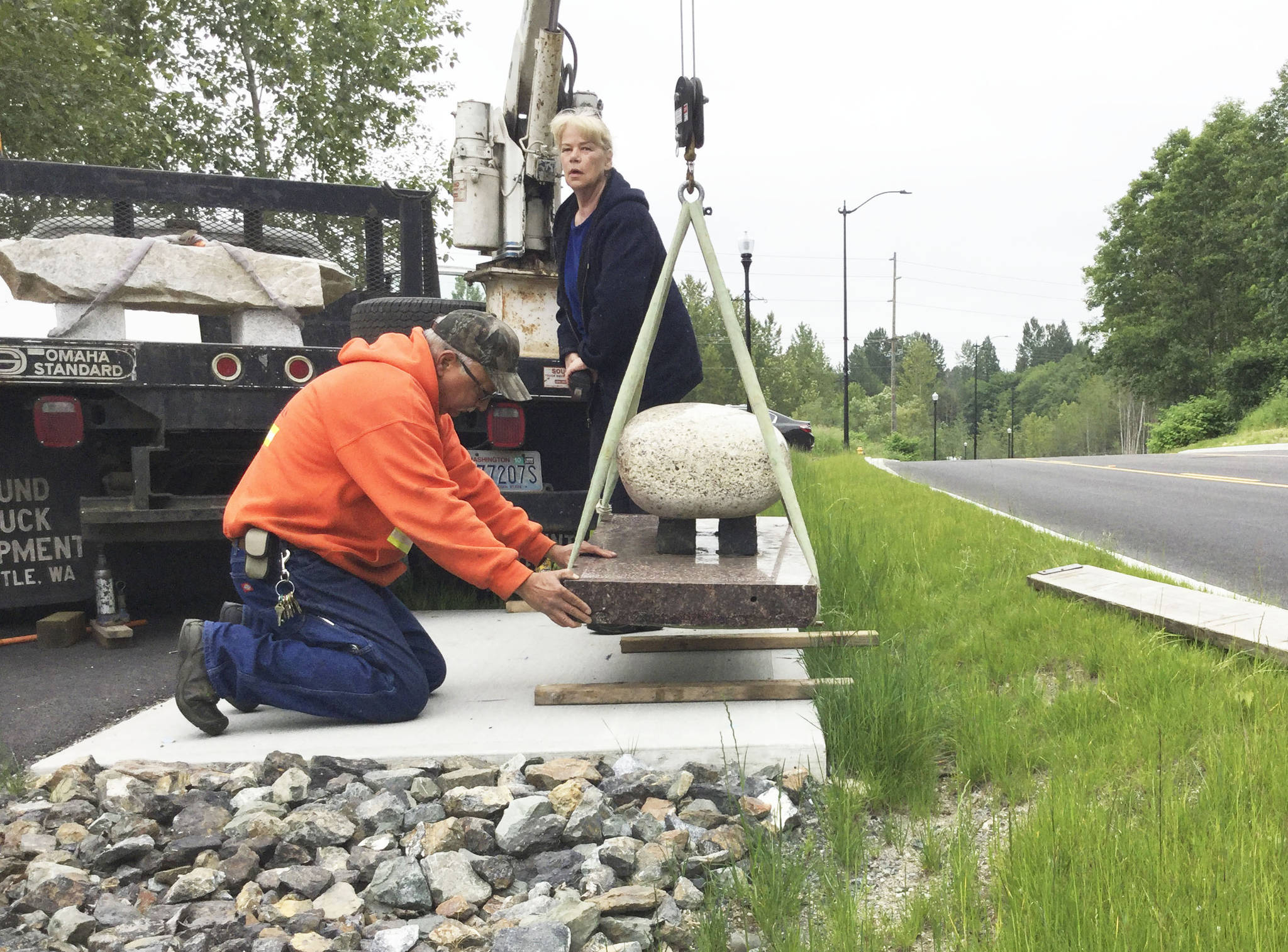 Stone artist Verena Schiffert controls the winch as Public Works employee Brock Talbot sets in place one of two sculpted benches being installed along Arlington Valley Road.